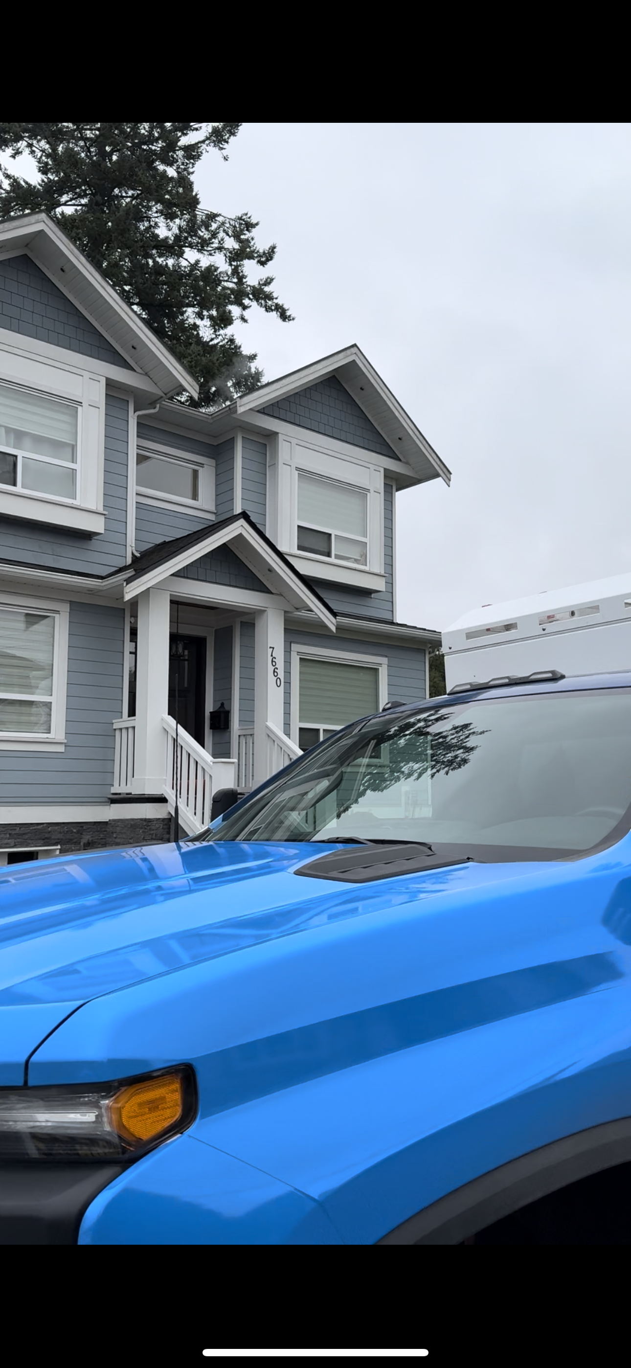 A blue car is parked in front of a house.