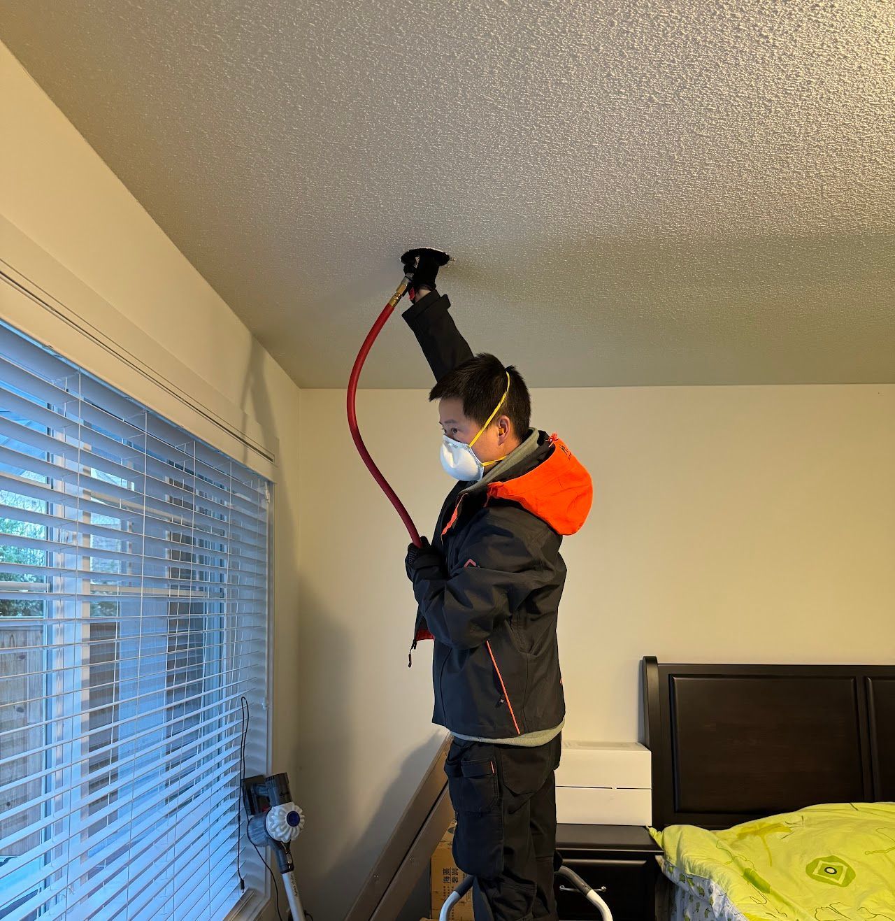 A man wearing a mask is working on a ceiling