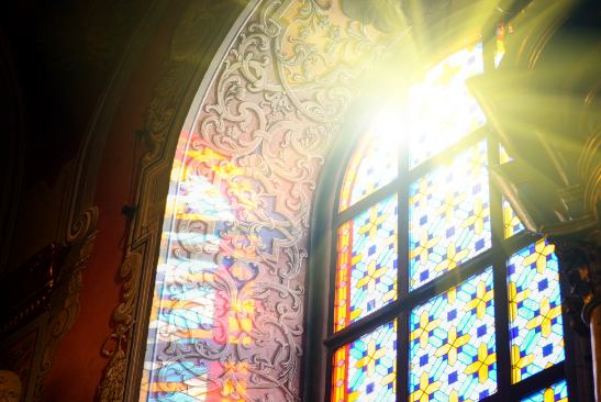 The sun is shining through a stained glass window in a church.