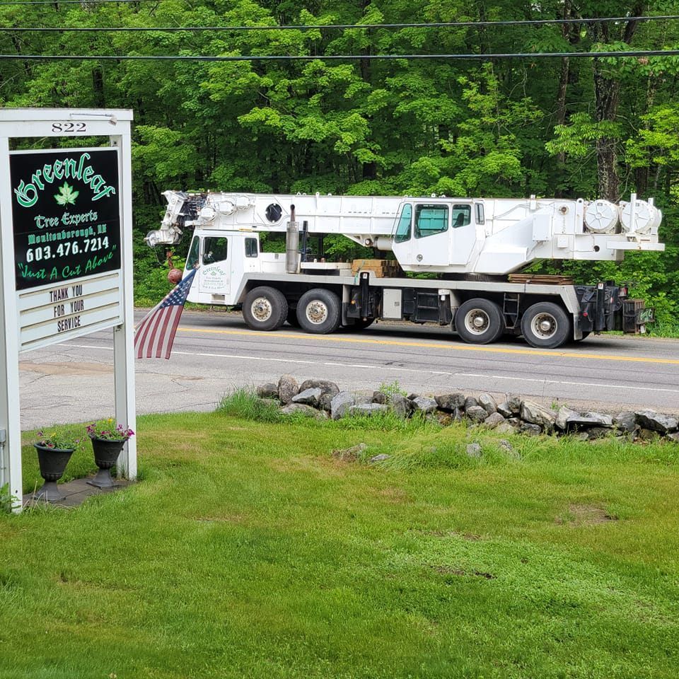 A crane truck is driving down the road next to a sign.