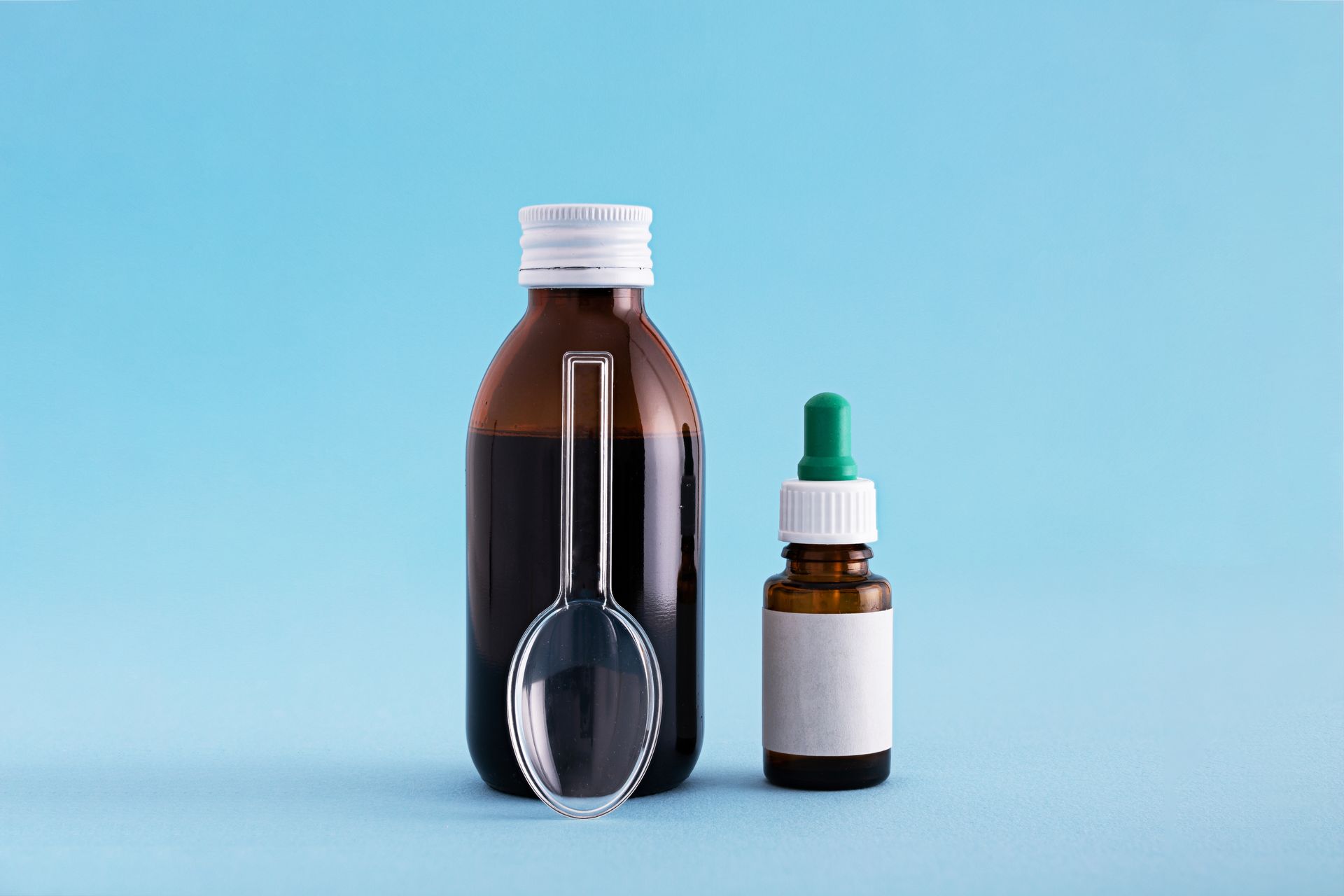 a bottle of cough syrup and a dropper with a magnifying glass on a blue background .
