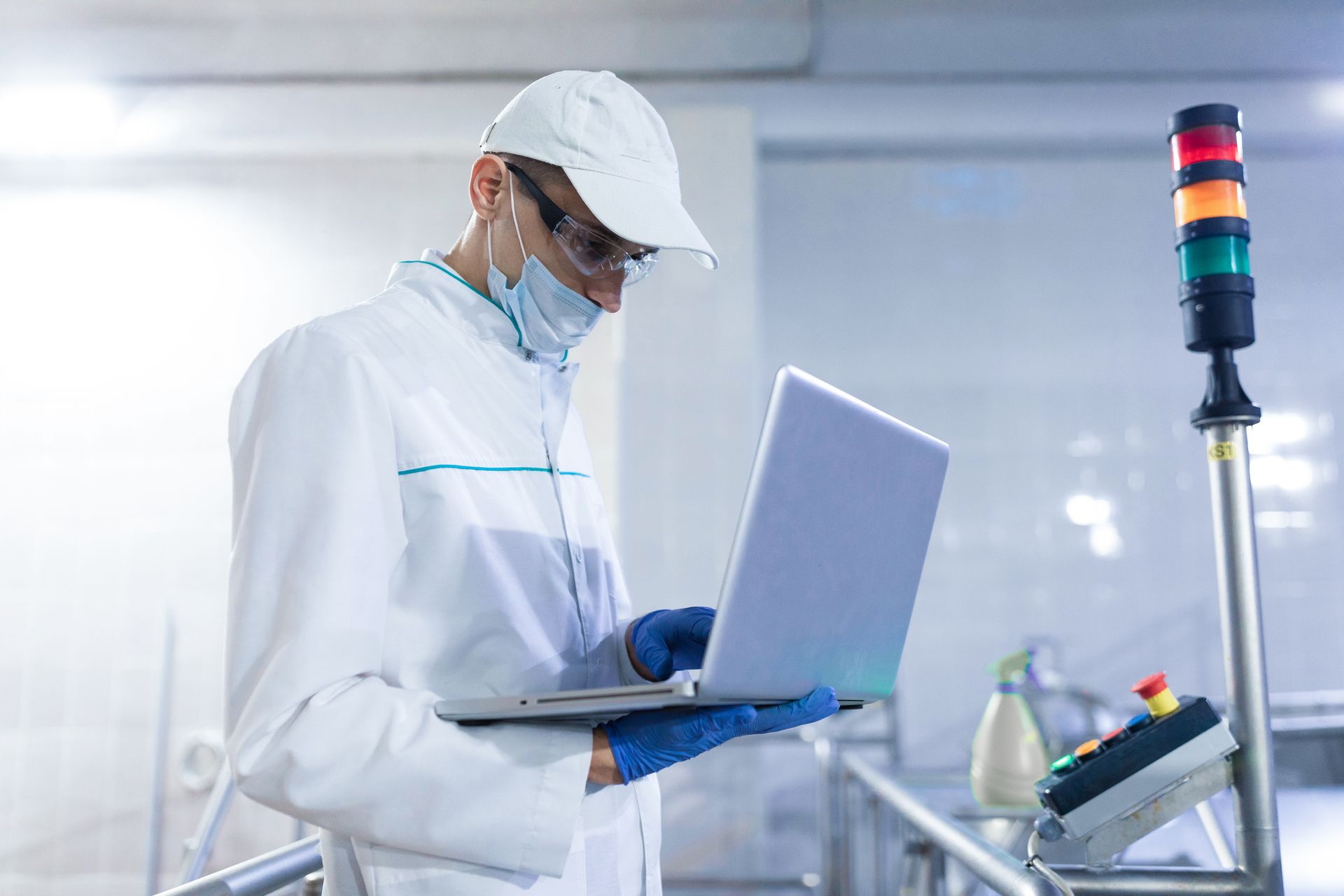 a man in a lab coat is using a laptop computer in a factory .