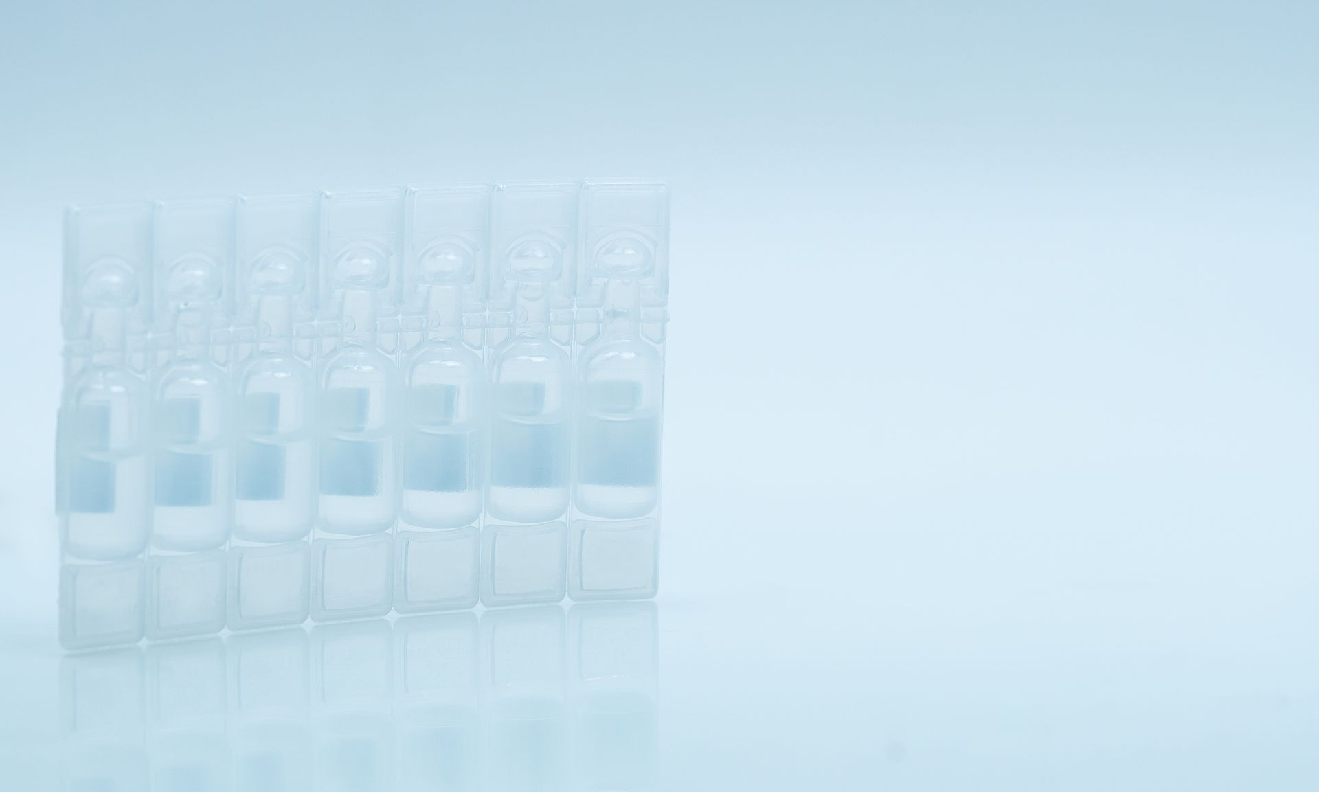 a row of clear plastic bottles on a blue surface .