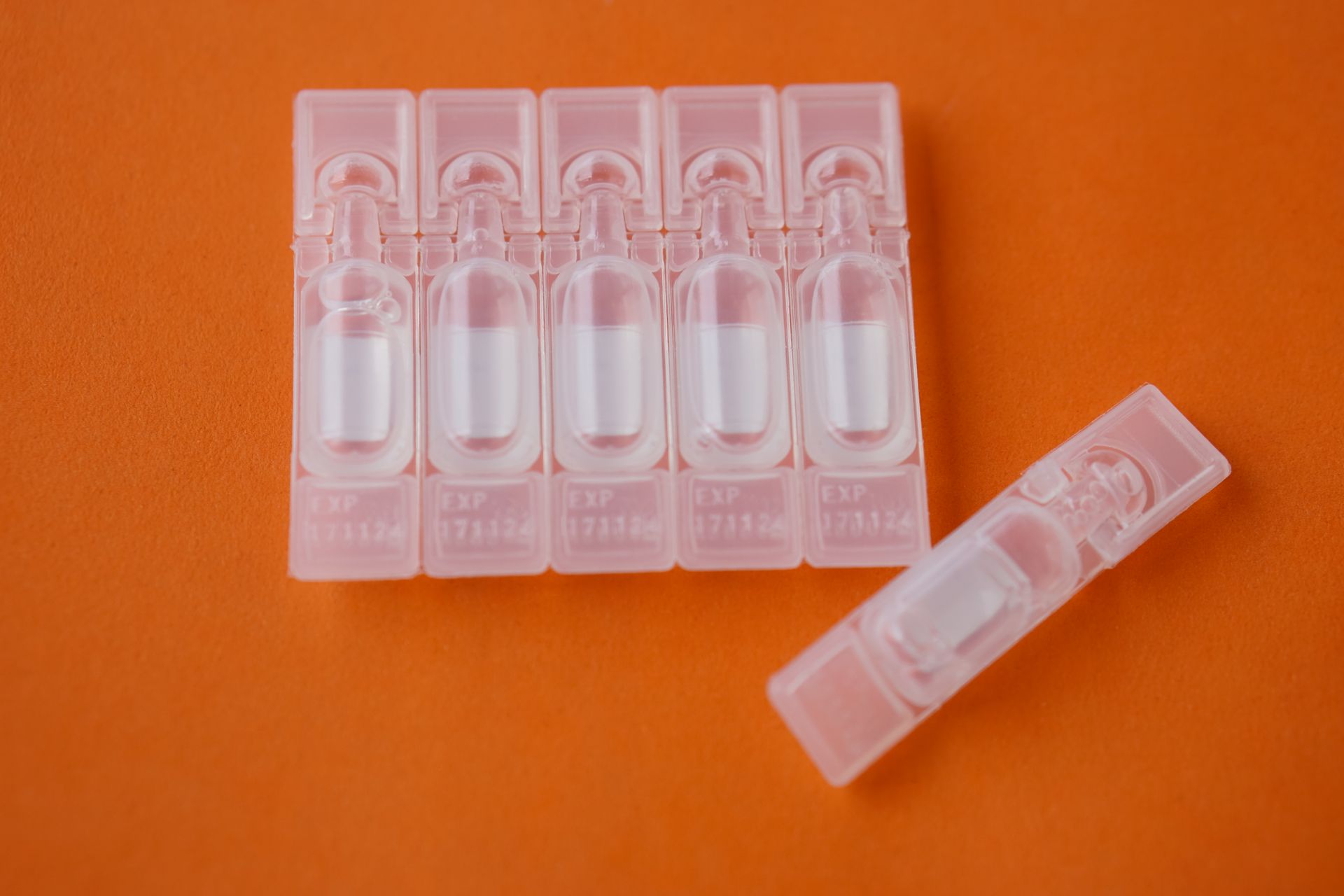 a row of plastic containers filled with liquid on an orange surface .