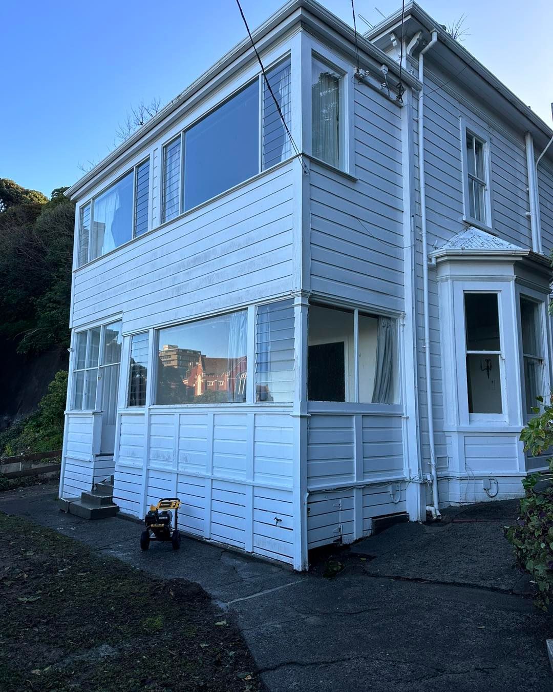 A large white house with a lot of windows is sitting on top of a hill.