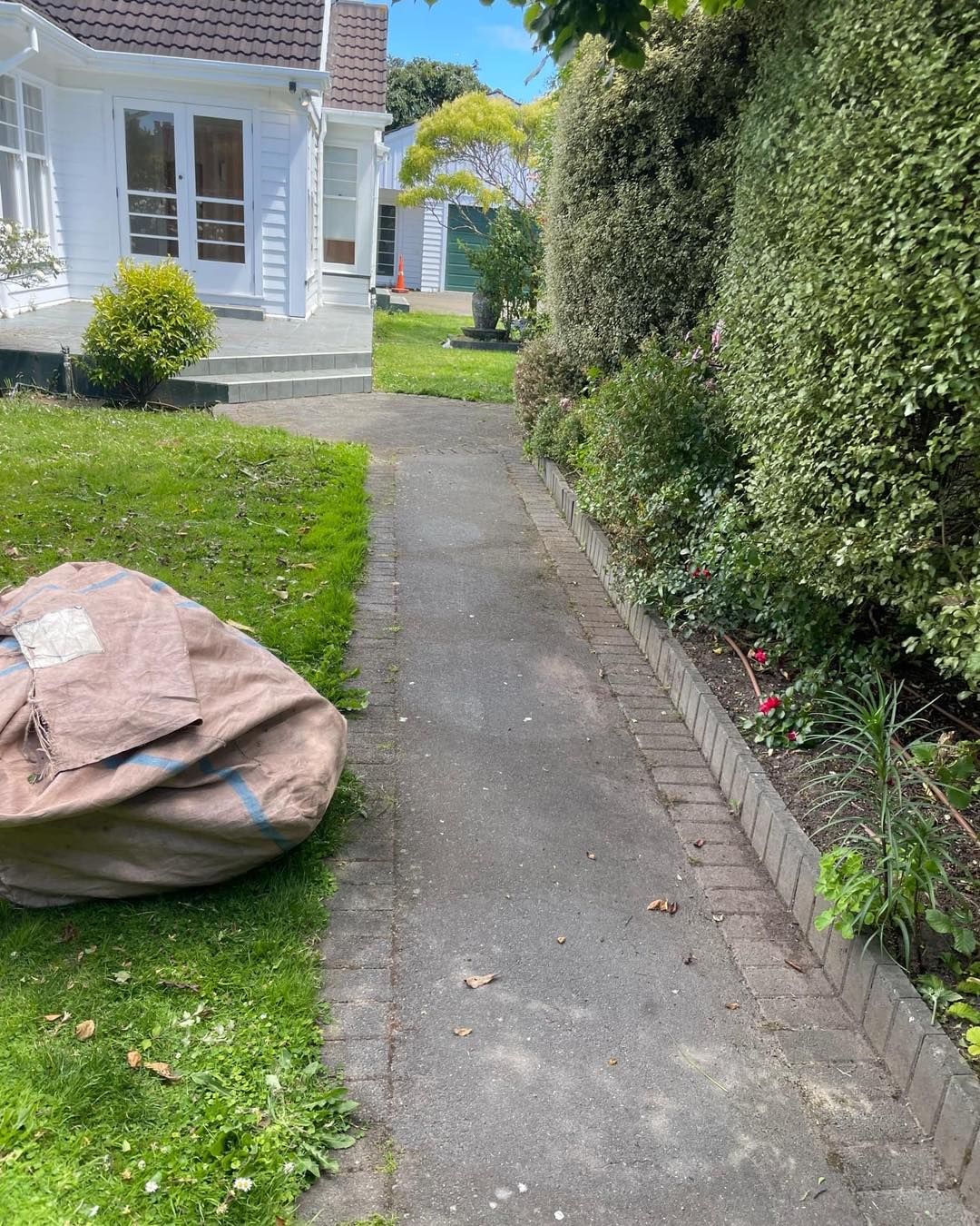 A bag is sitting on the sidewalk in front of a house.