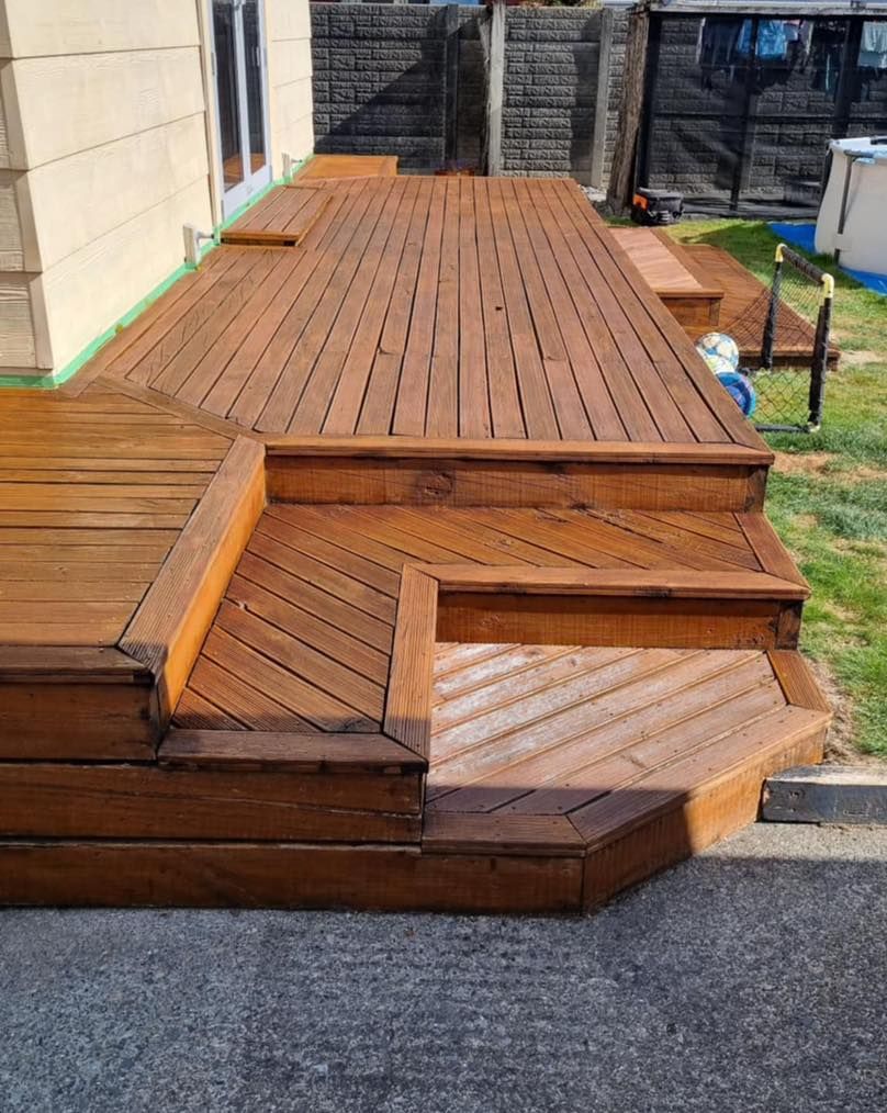 A wooden deck with stairs leading up to it and a house in the background.