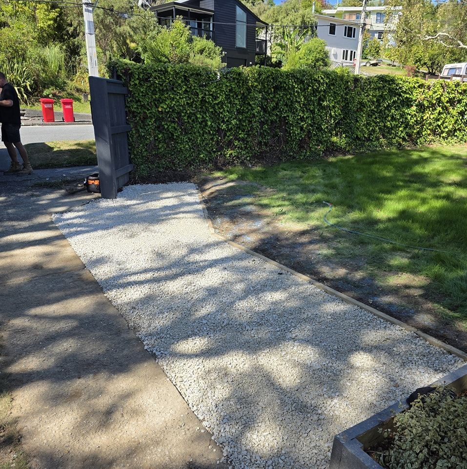 A man is standing next to a gravel path in a yard