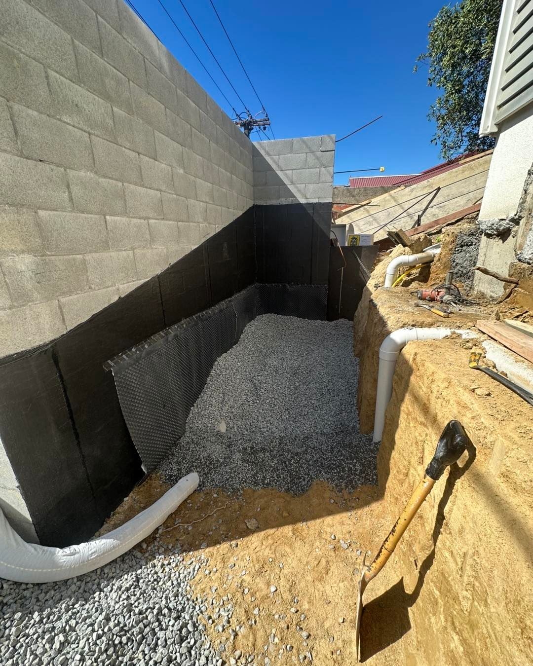 A shovel is sitting in the dirt next to a pile of gravel.