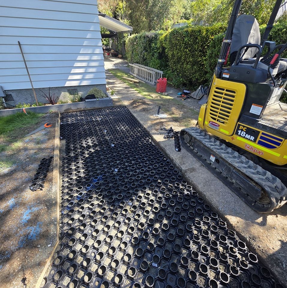 A yellow and black excavator is parked next to a house.
