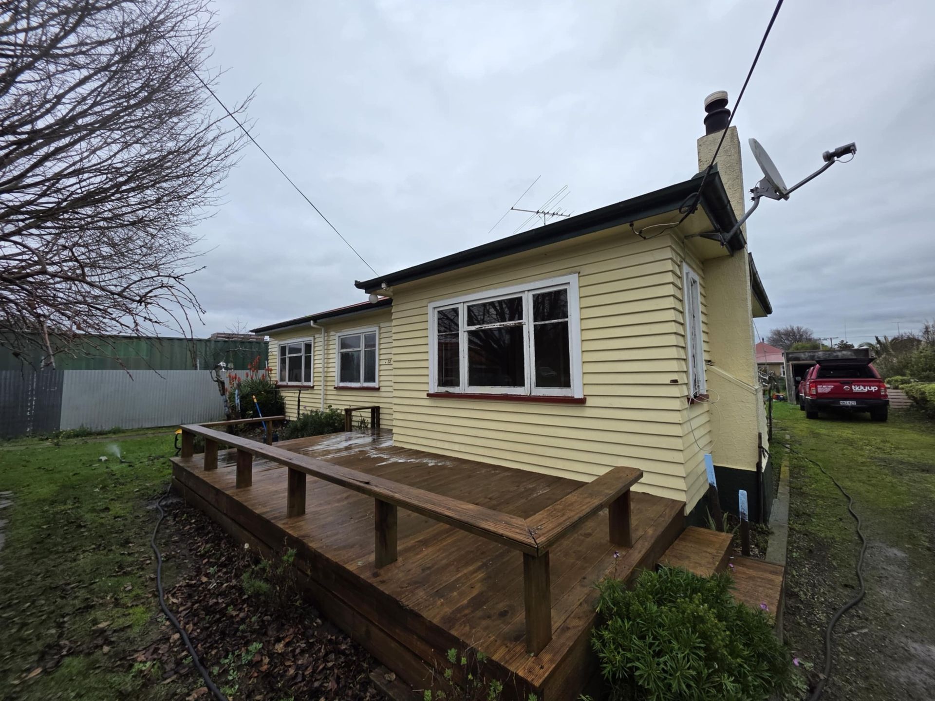 A small yellow house with a wooden deck in front of it.