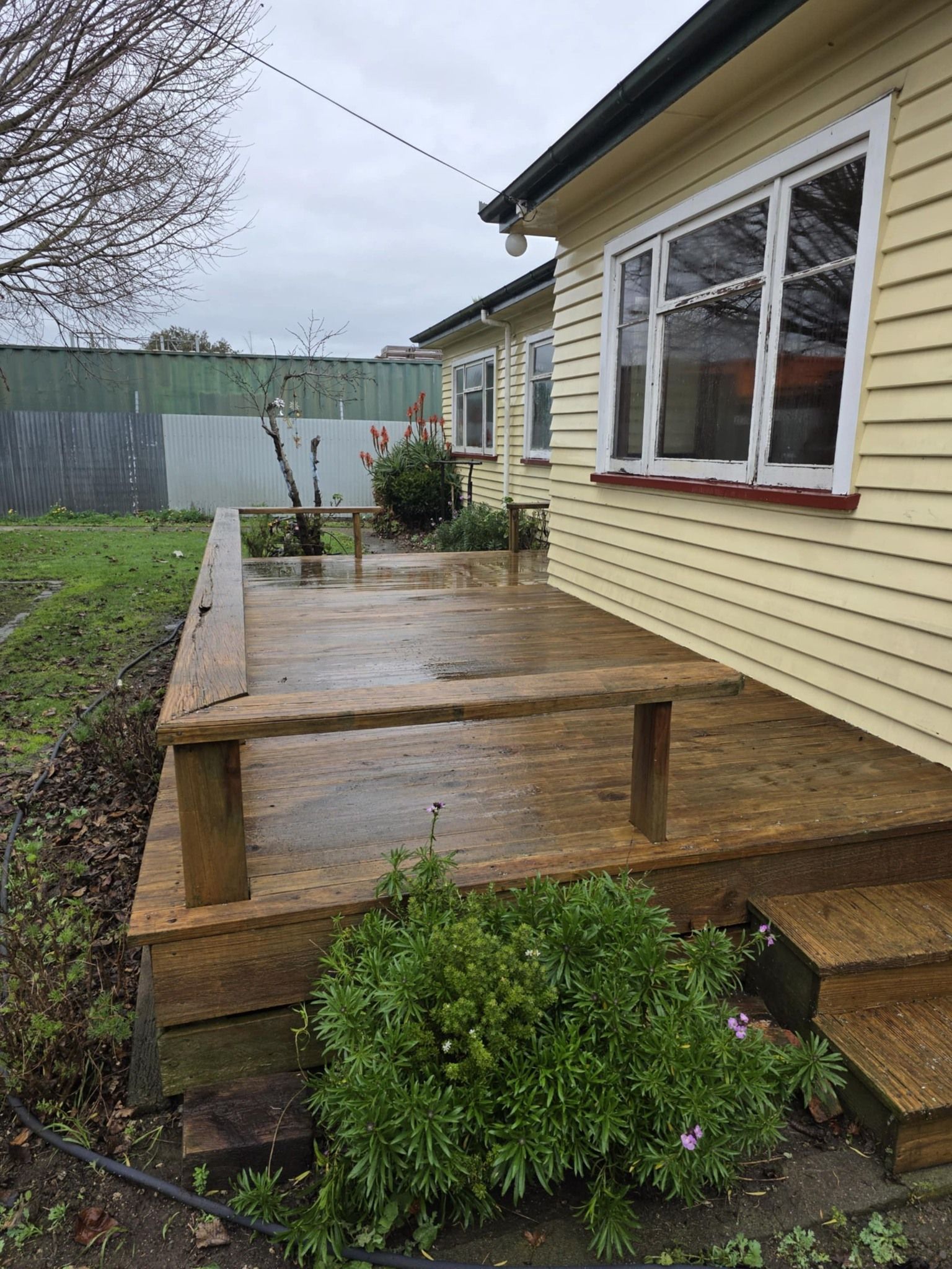 A yellow house with a wooden deck in front of it.