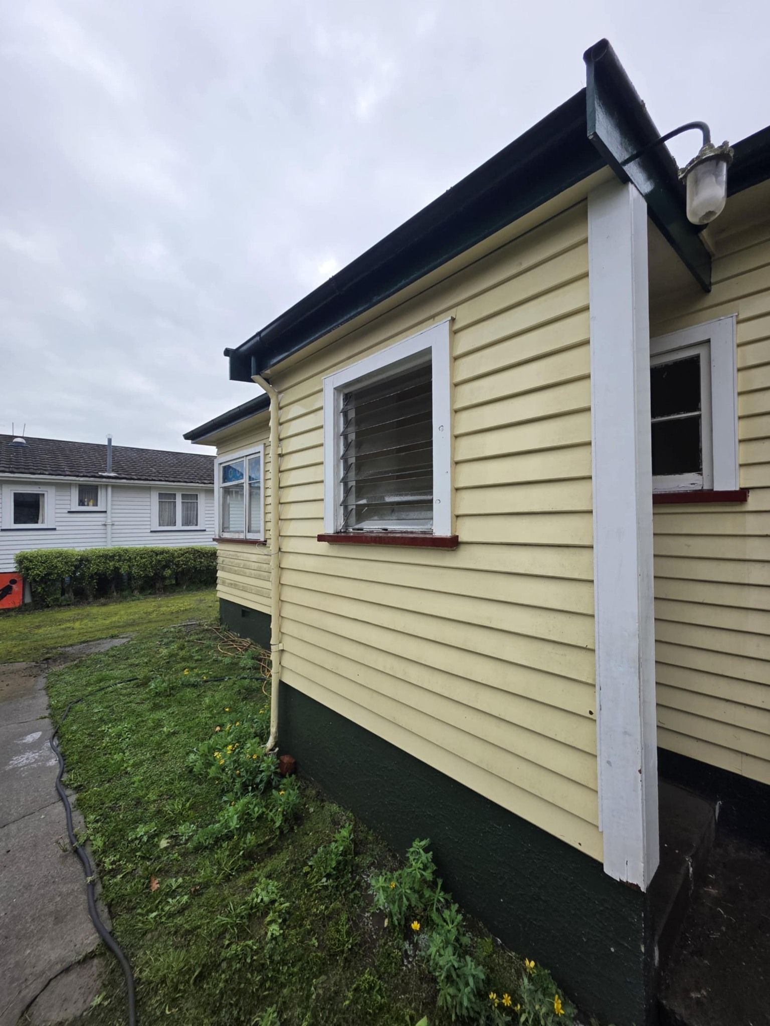 A yellow house with a black roof and white trim