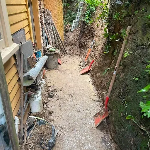 A dirt path leading to a house with shovels on the side of it.