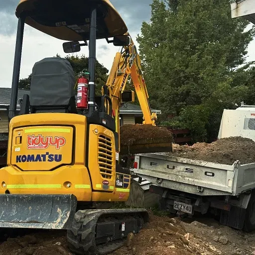 A yellow komatsu excavator is loading dirt into a dump truck