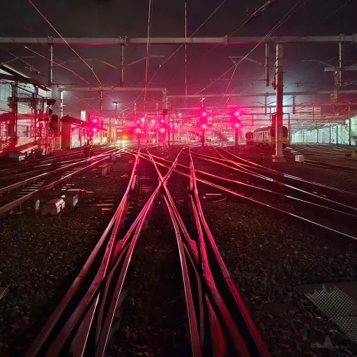 A train station at night with red lights on the tracks