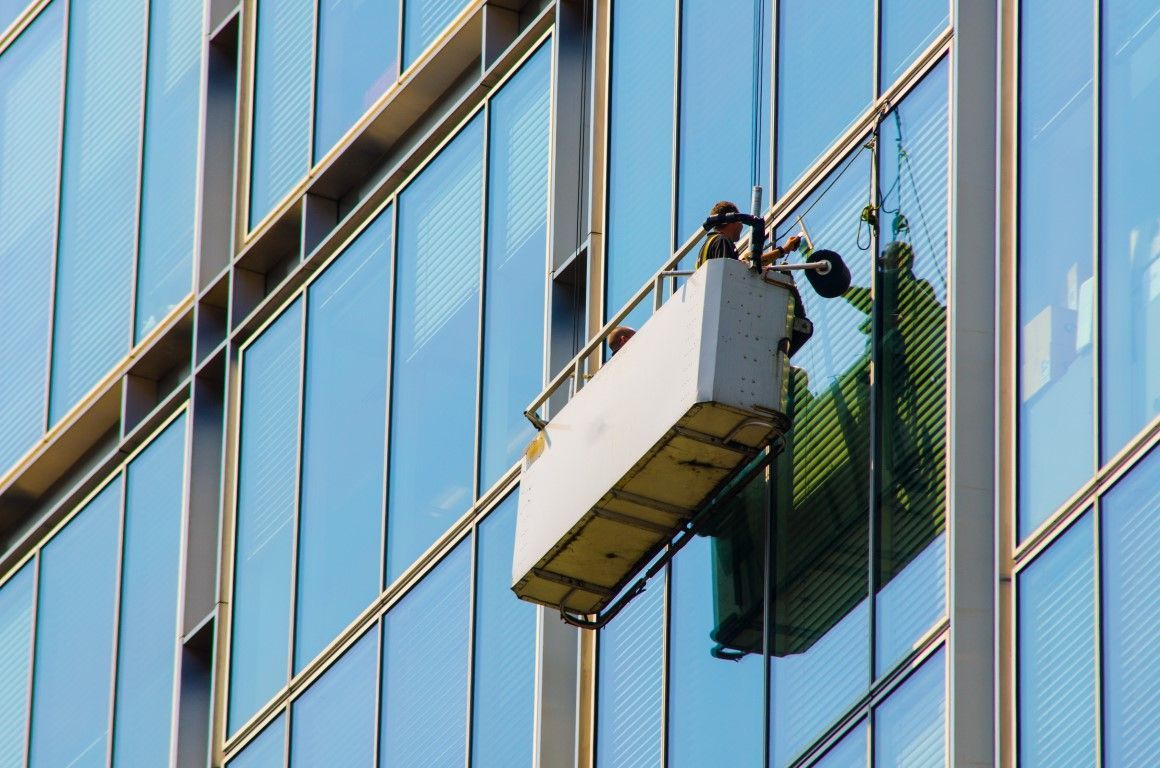 A man is cleaning the windows of a tall building.