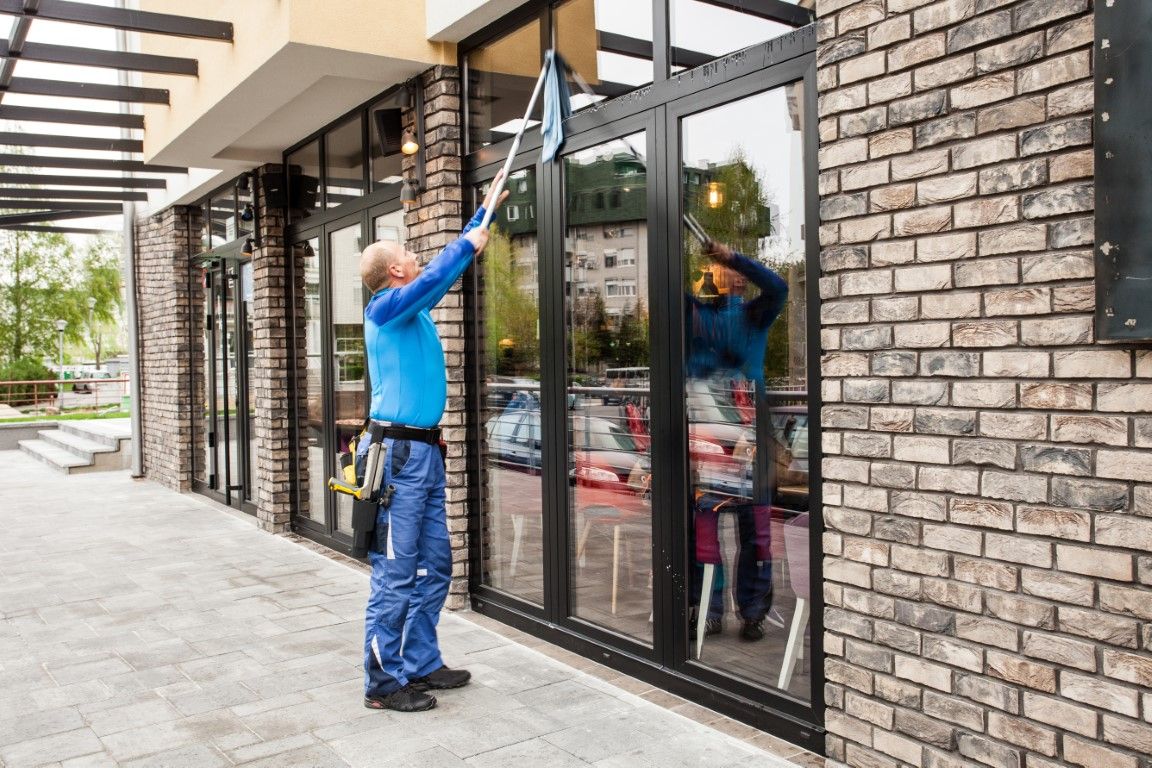 A man is cleaning the windows of a building with a towel.