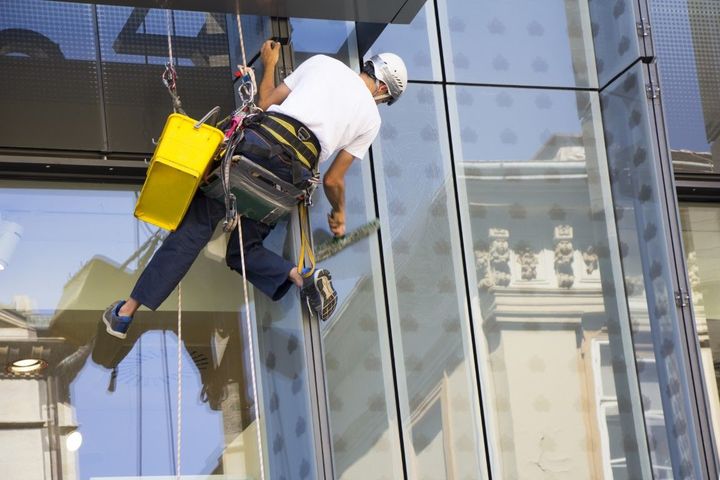 A man is cleaning the windows of a tall building.