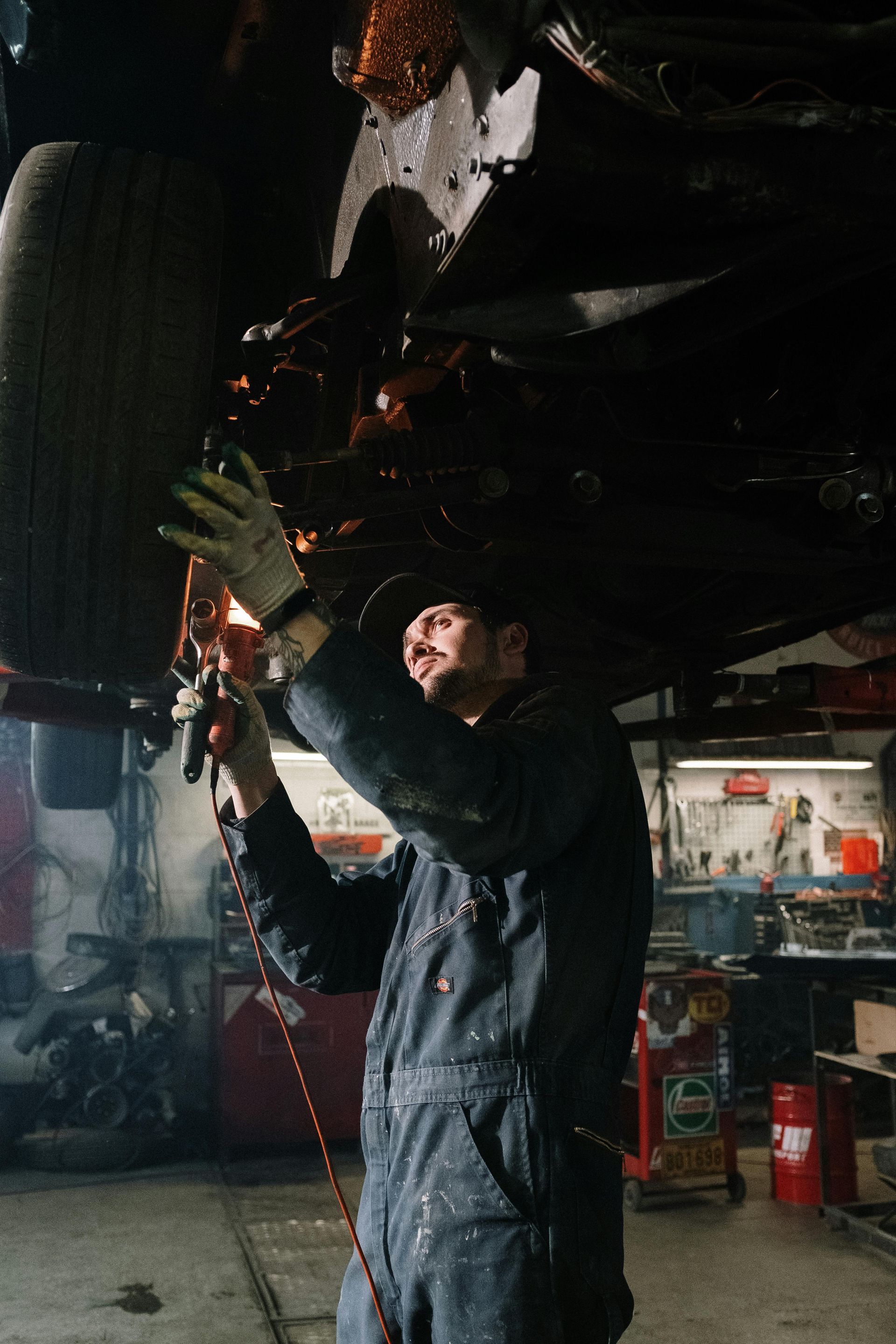 A man is working under a car in a garage.