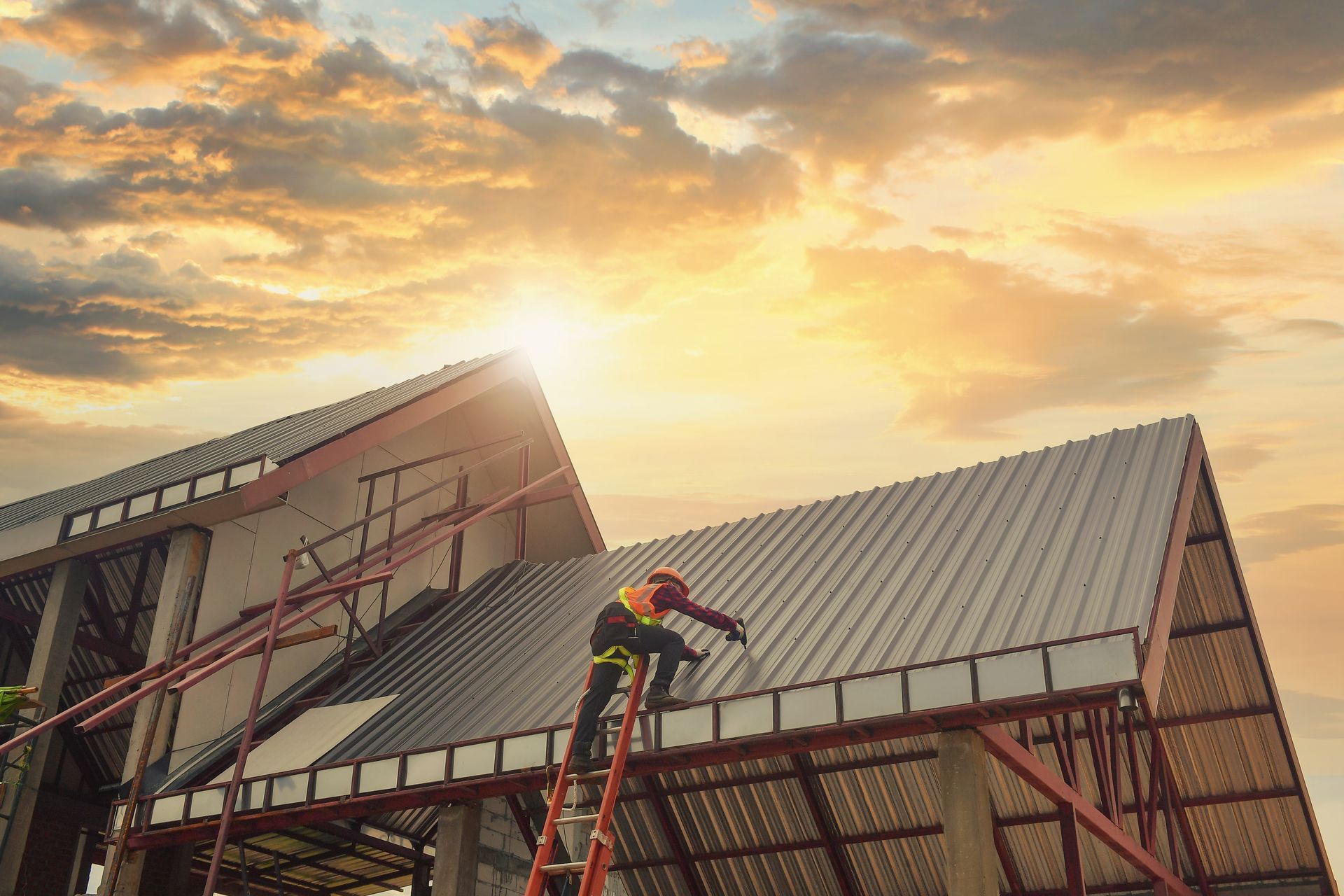 Workers installing metal roofing on a building, sunset in background.
