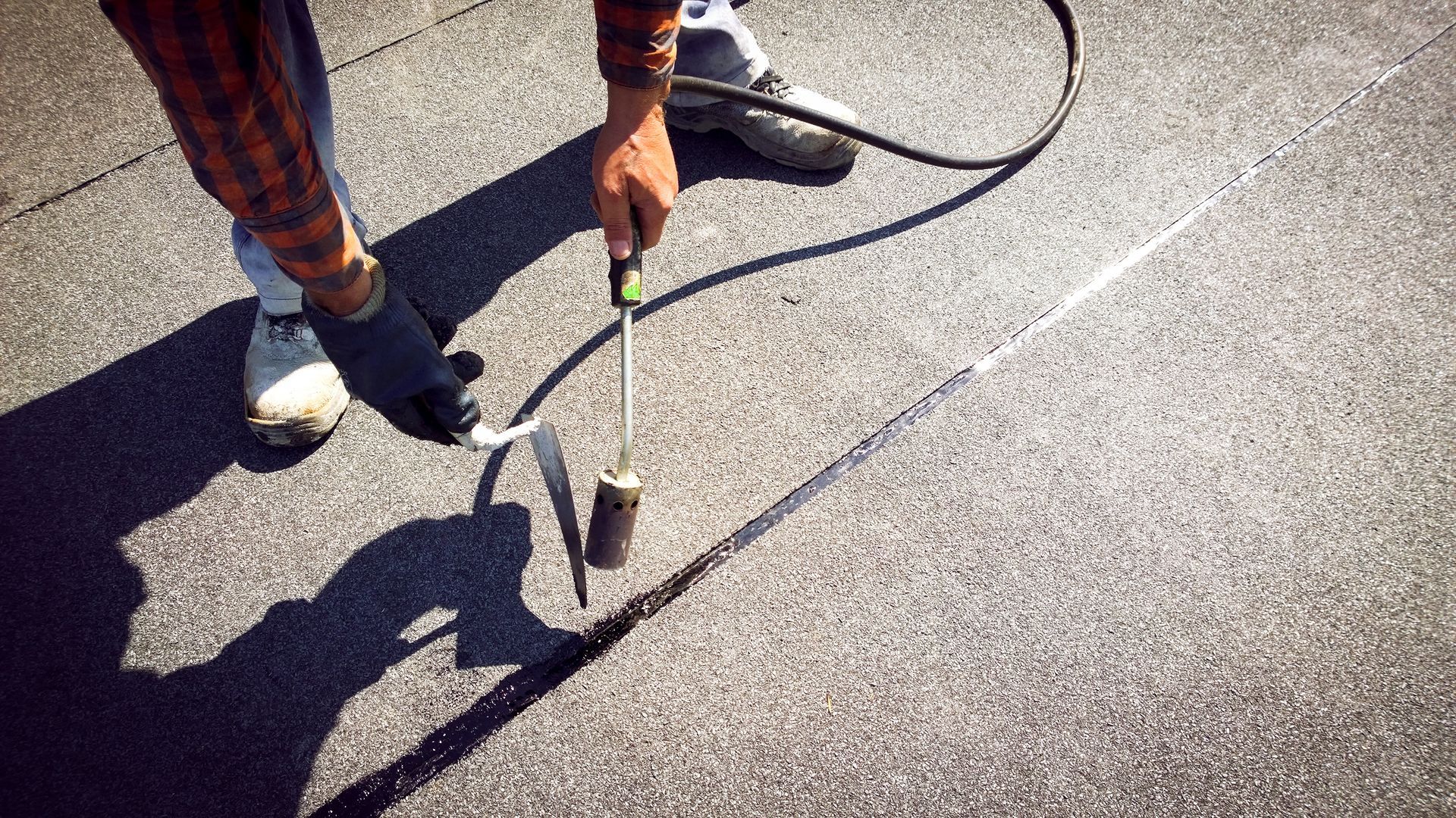 Person using a torch to seal roofing material.