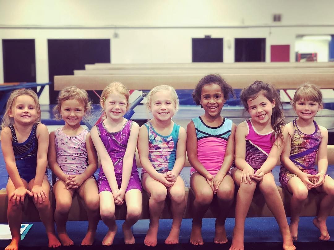 A group of young girls are sitting on a bench and smiling