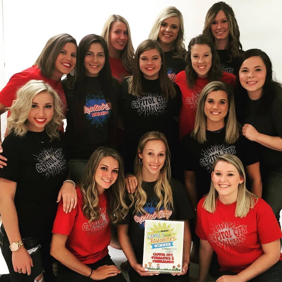 A group of women are posing for a picture and one of them is holding a book