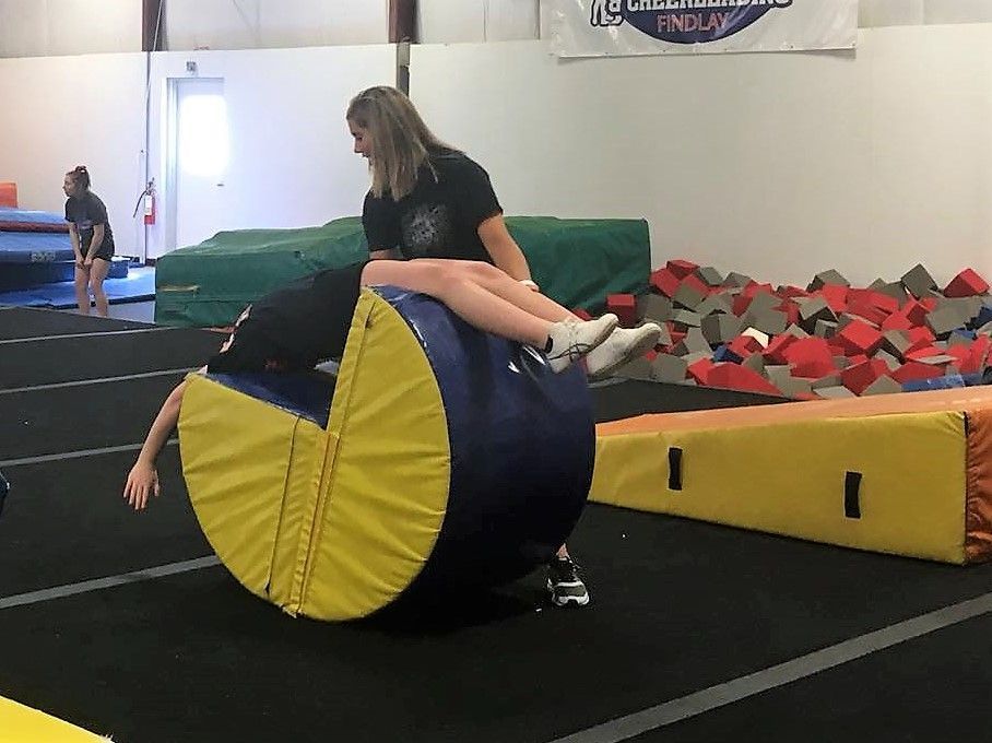 A woman is teaching a child how to balance on a balance beam.