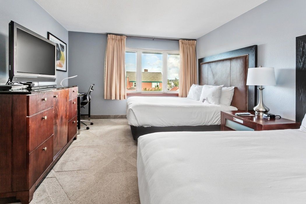 a hotel room with two beds and a flat screen tv