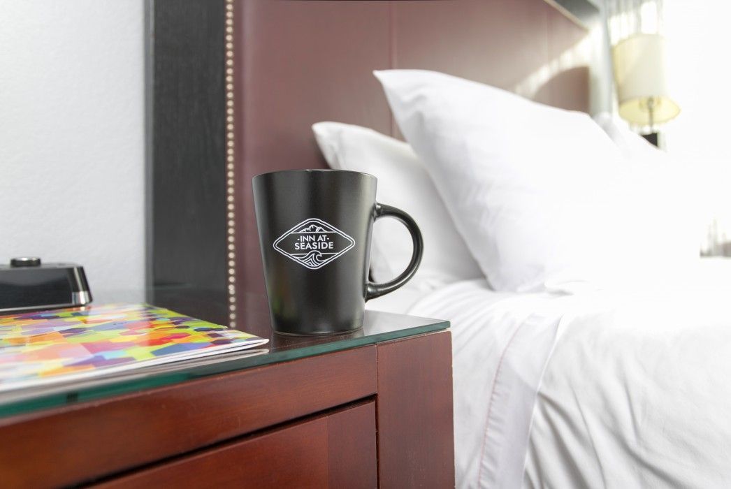 a coffee mug is sitting on a nightstand next to a bed .