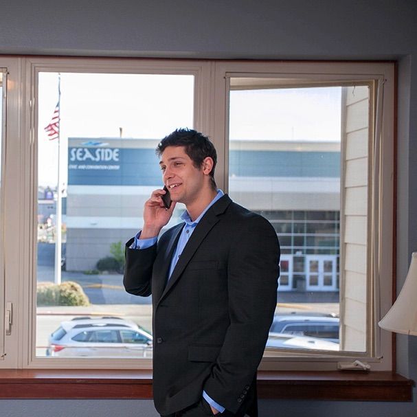 a man in a suit is talking on a cell phone in front of a window that says seaside
