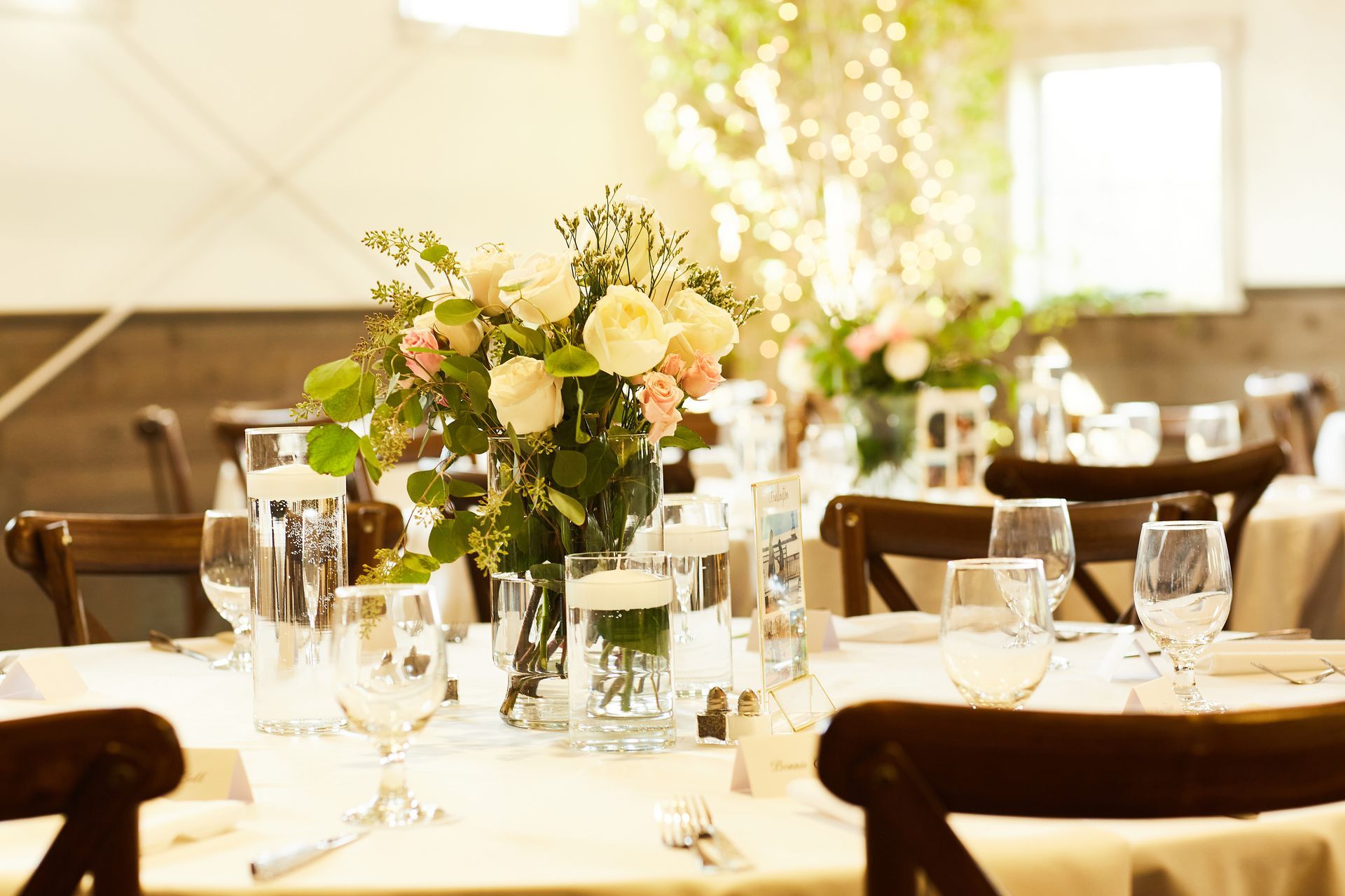 A table set for a wedding reception with a vase of flowers on it.