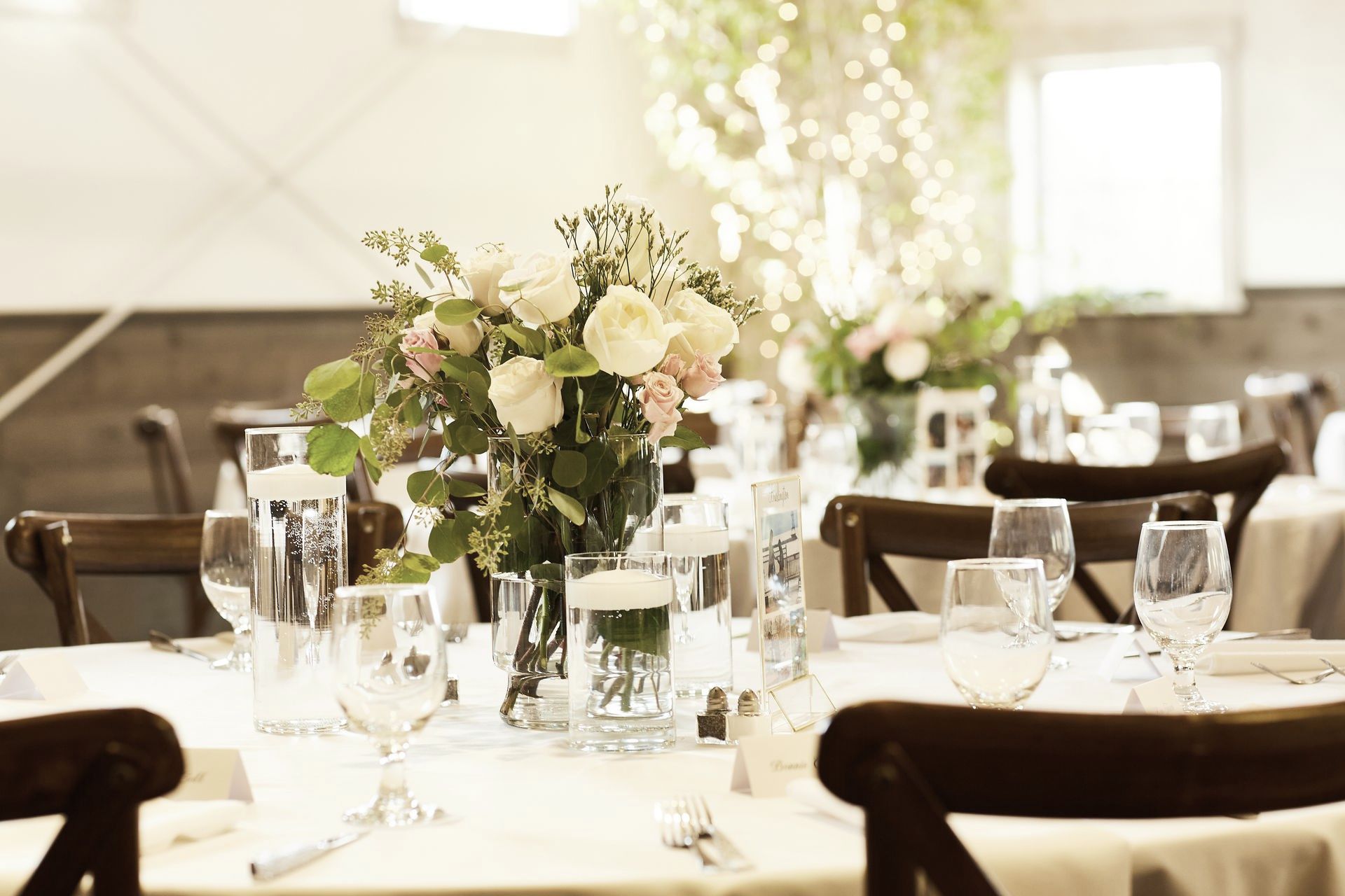 A table set for a wedding reception with a vase of flowers on it.
