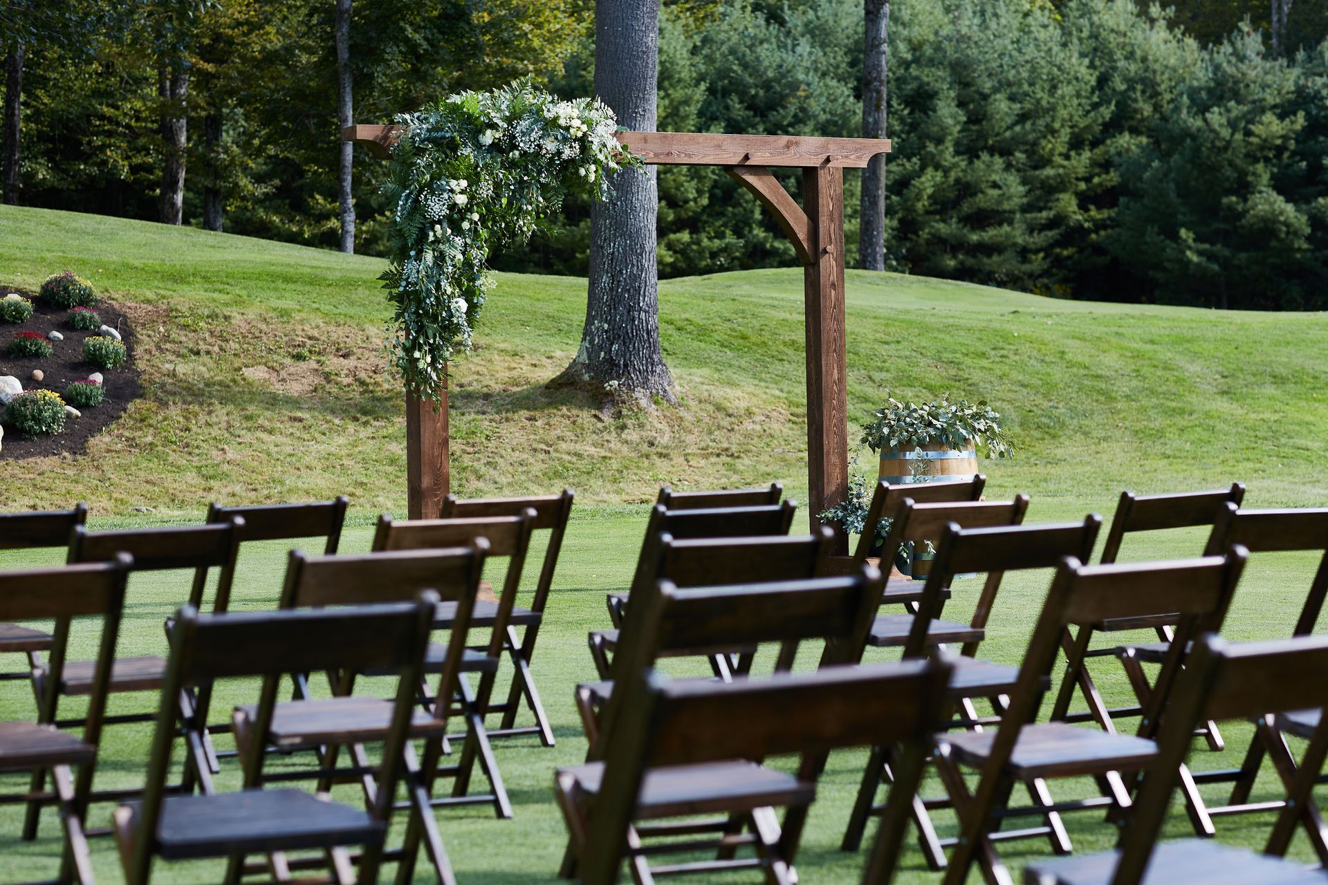A row of wooden folding chairs are lined up on a lush green field.