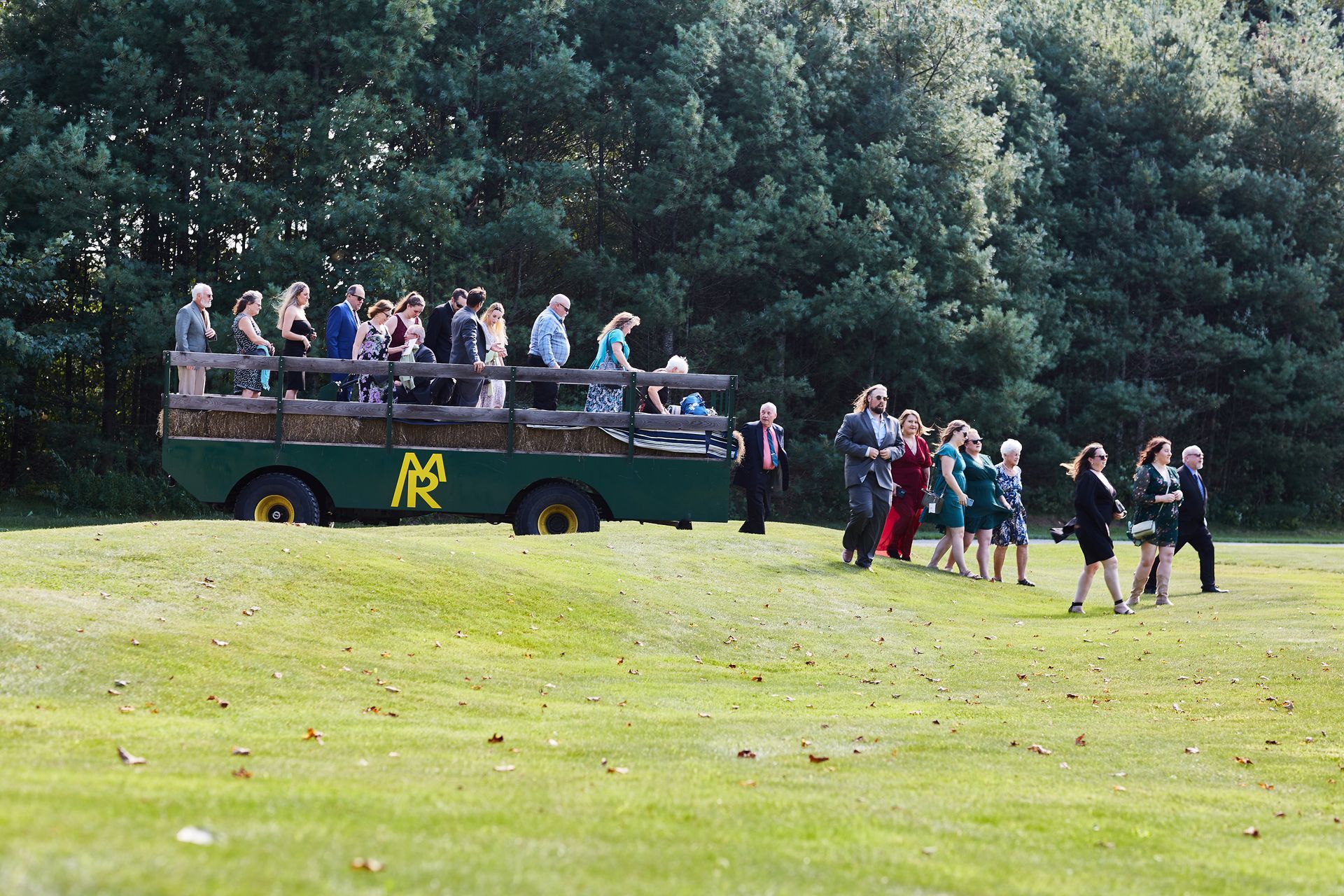A group of people are walking in front of a bus with the letter r on it