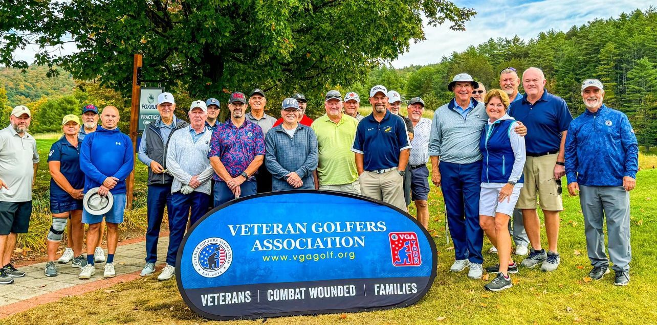 Group of golfers pose behind a banner that says