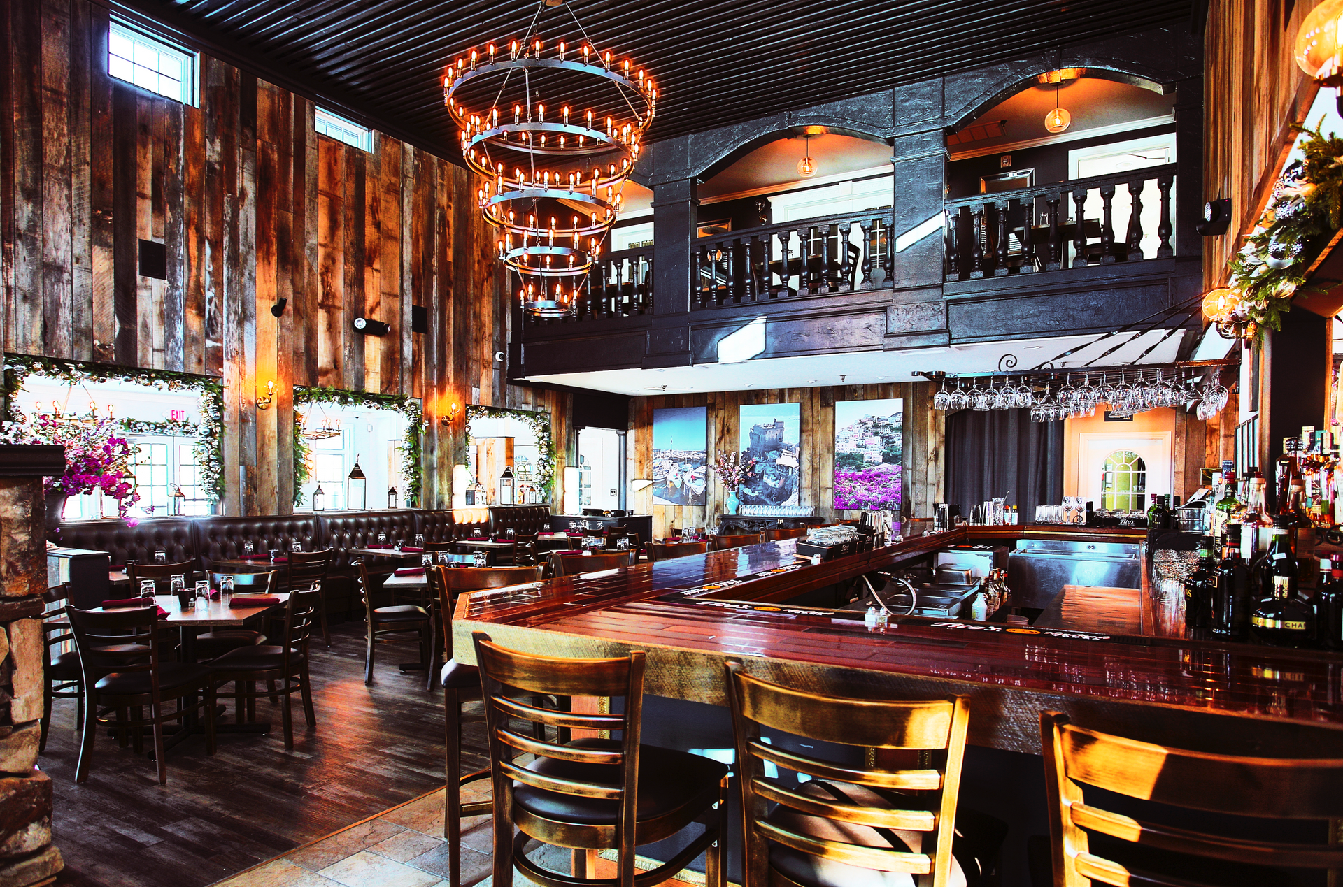 Interior of rustic restaurant with wood paneling, bar, tables, and a large chandelier.
