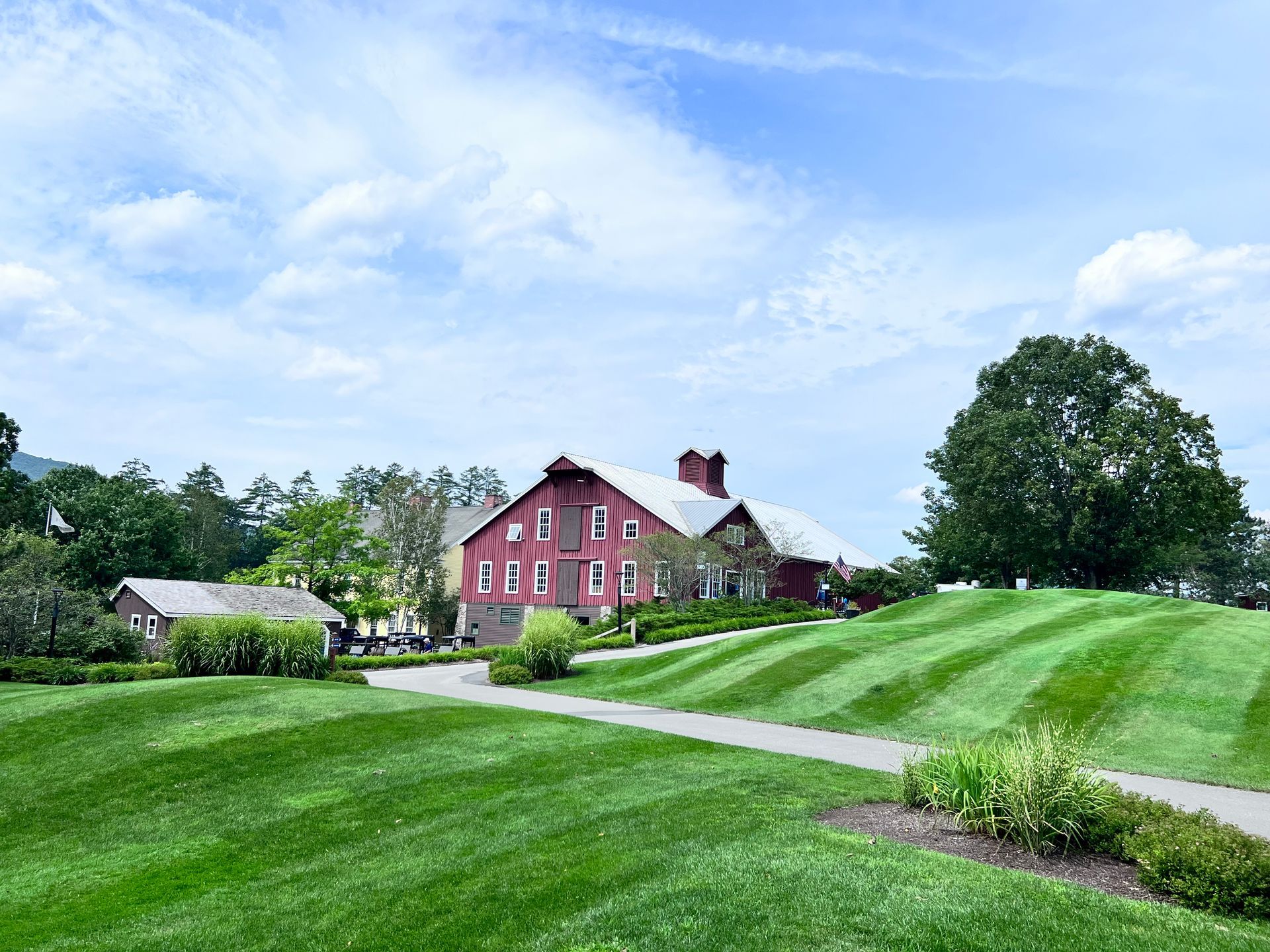 A large red barn is sitting on top of a lush green hill.