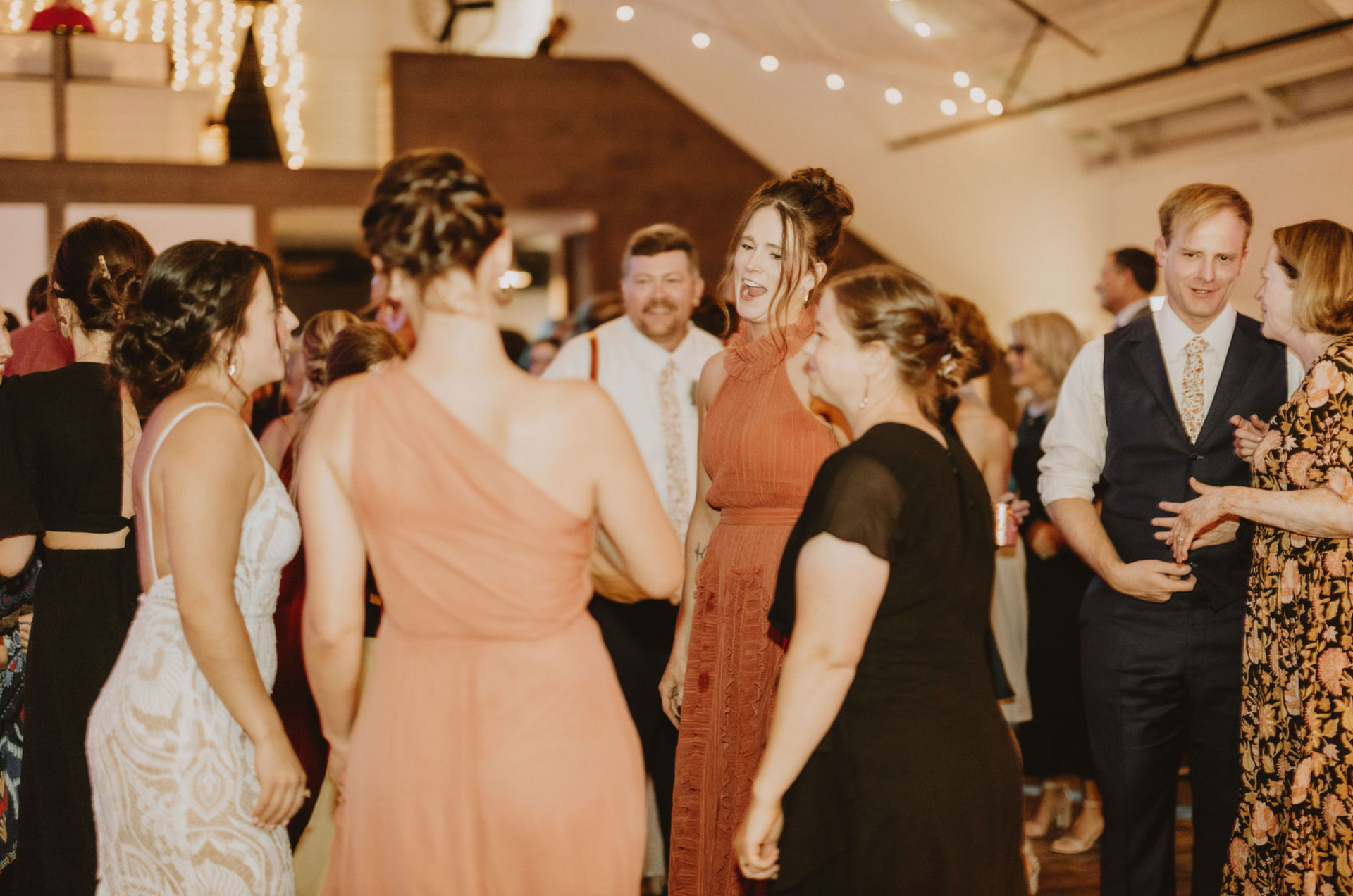 A group of people are dancing at a wedding reception.