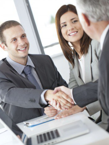 a man and a woman shaking hands with a loan officer while sitting at a table