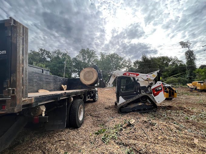 A bulldozer is sitting next to a flatbed truck in a field.