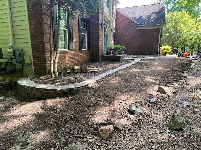 A brick house with a dirt driveway in front of it.
