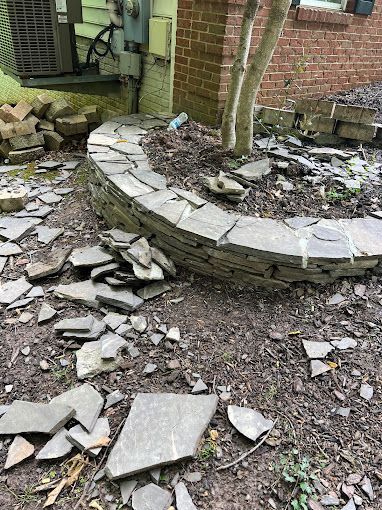 A pile of rocks is laying on the ground in front of a brick building.