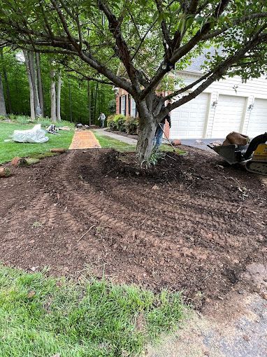 A man is standing next to a pile of mulch in a yard.
