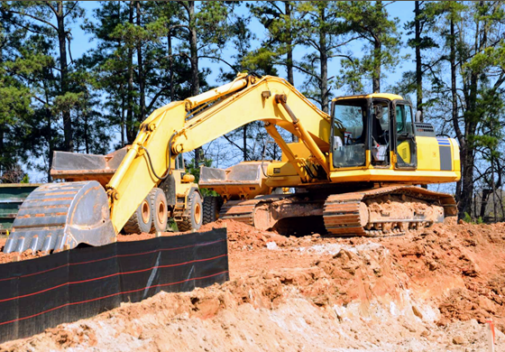 A yellow excavator is moving dirt on a construction site.