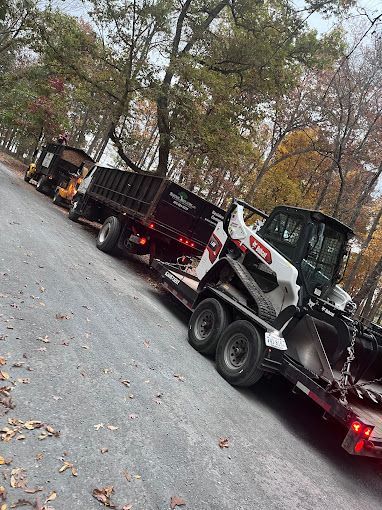 A truck is towing a bulldozer on a trailer down a road.
