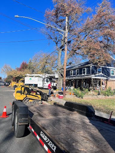A trailer with a bulldozer on it is parked on the side of the road.