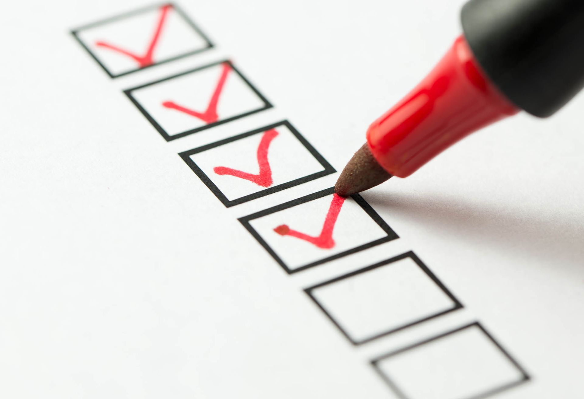 Red pen marking checkboxes on a checklist, with several red checkmarks and one blank box.