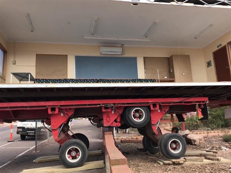 Red truck chassis tilted on a ramp outside a building with a garage-style doorway Red truck chassis tilted on a ramp outside a building with a garage-style doorway